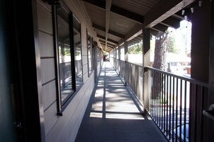 Um corredor coberto com guarda-corrimão de metal, grandes janelas e vista para a rua.