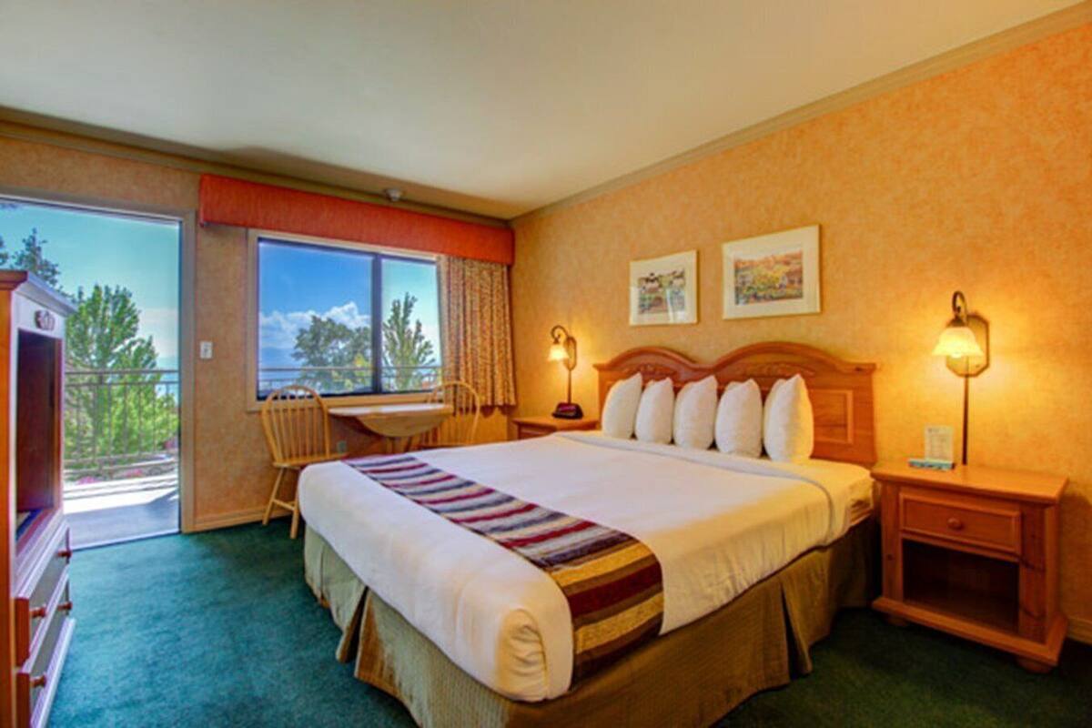 A hotel room with a large bed, a desk, and a view of the outdoors.