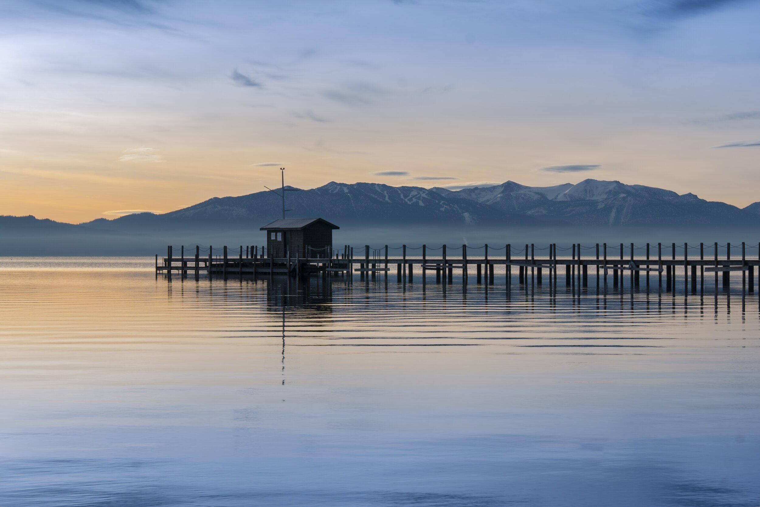 Eine hölzerne Pier, die sich in ruhiges Wasser erstreckt, mit einer kleinen Hütte am Ende.