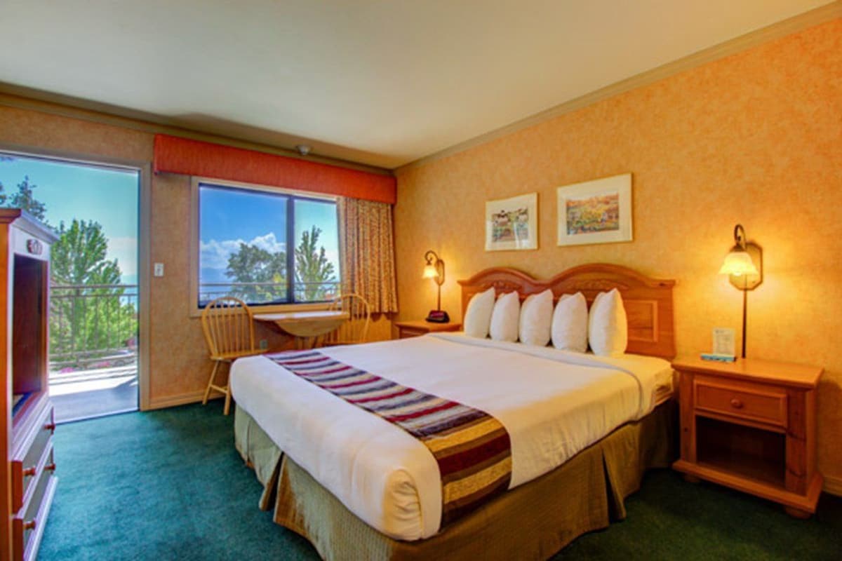 Una habitación de hotel con una cama grande, un escritorio y una silla cerca de una ventana.