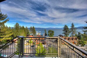 A view from a balcony overlooking a parking lot, a row of houses, and a body of water with mountains in the distance. - Pepper Tree Inn (Tahoe City)