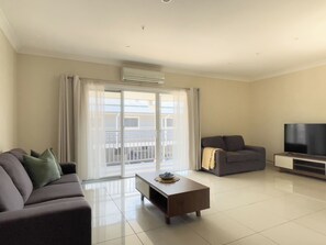 Una sala de estar moderna con sofá, mesa de centro y televisor.