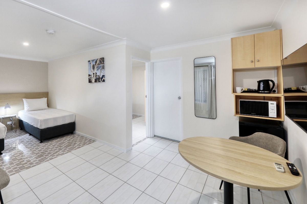 Una habitación de hotel con cama, escritorio, silla, microondas y cafetera.