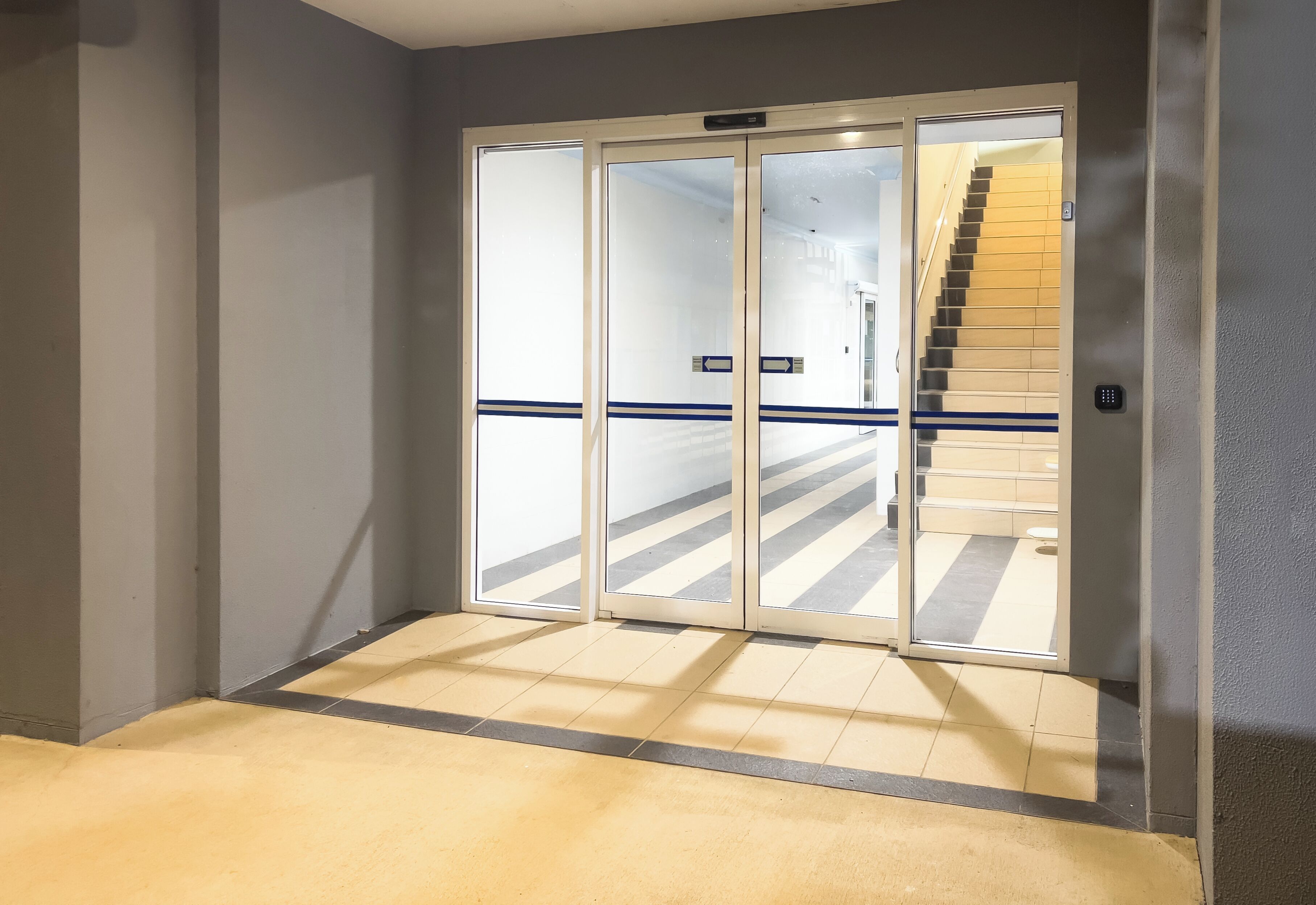 Un couloir avec une porte vitrée donnant sur un escalier.
