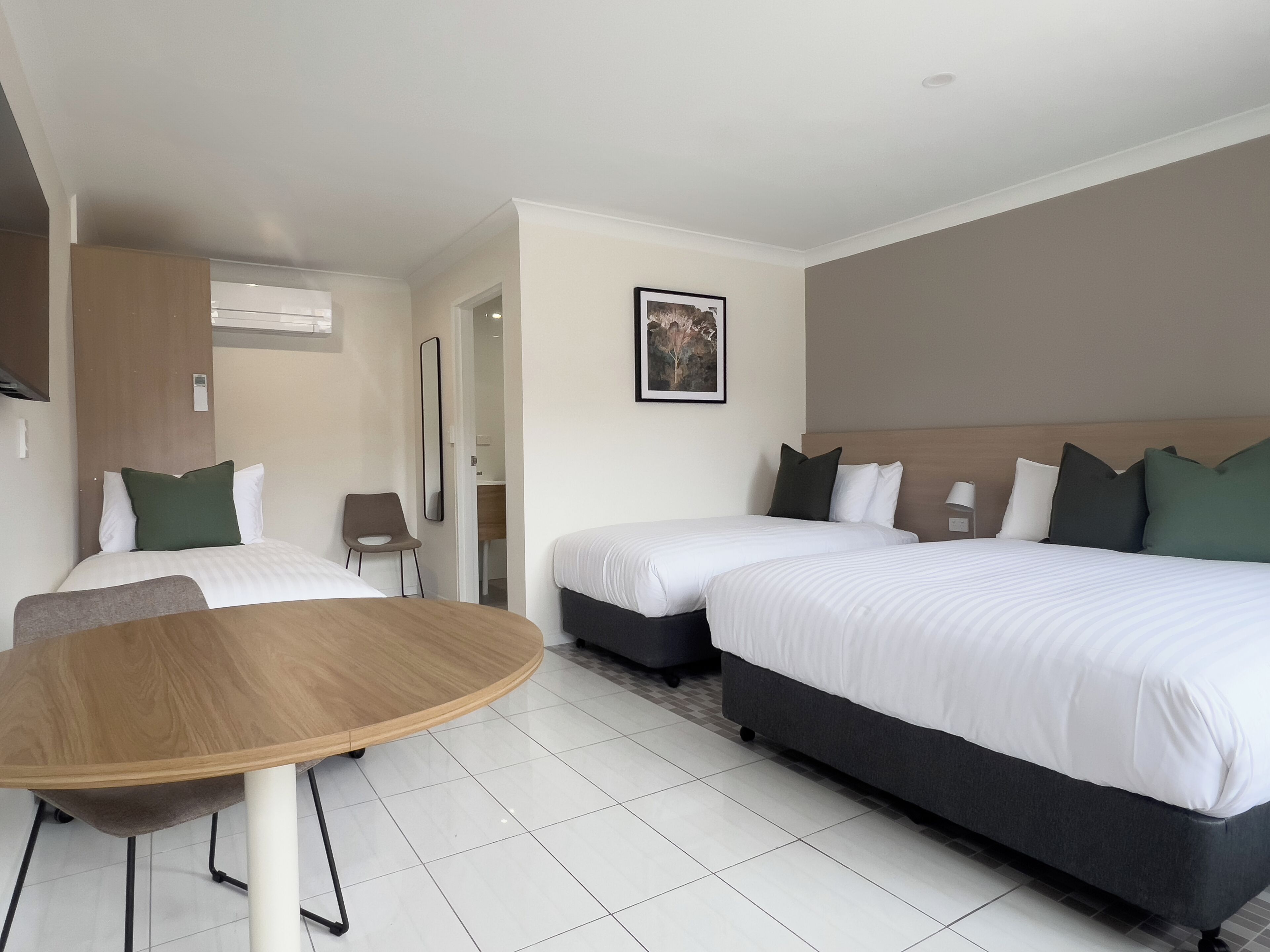 A hotel room with two beds, a wooden table, and a chair.