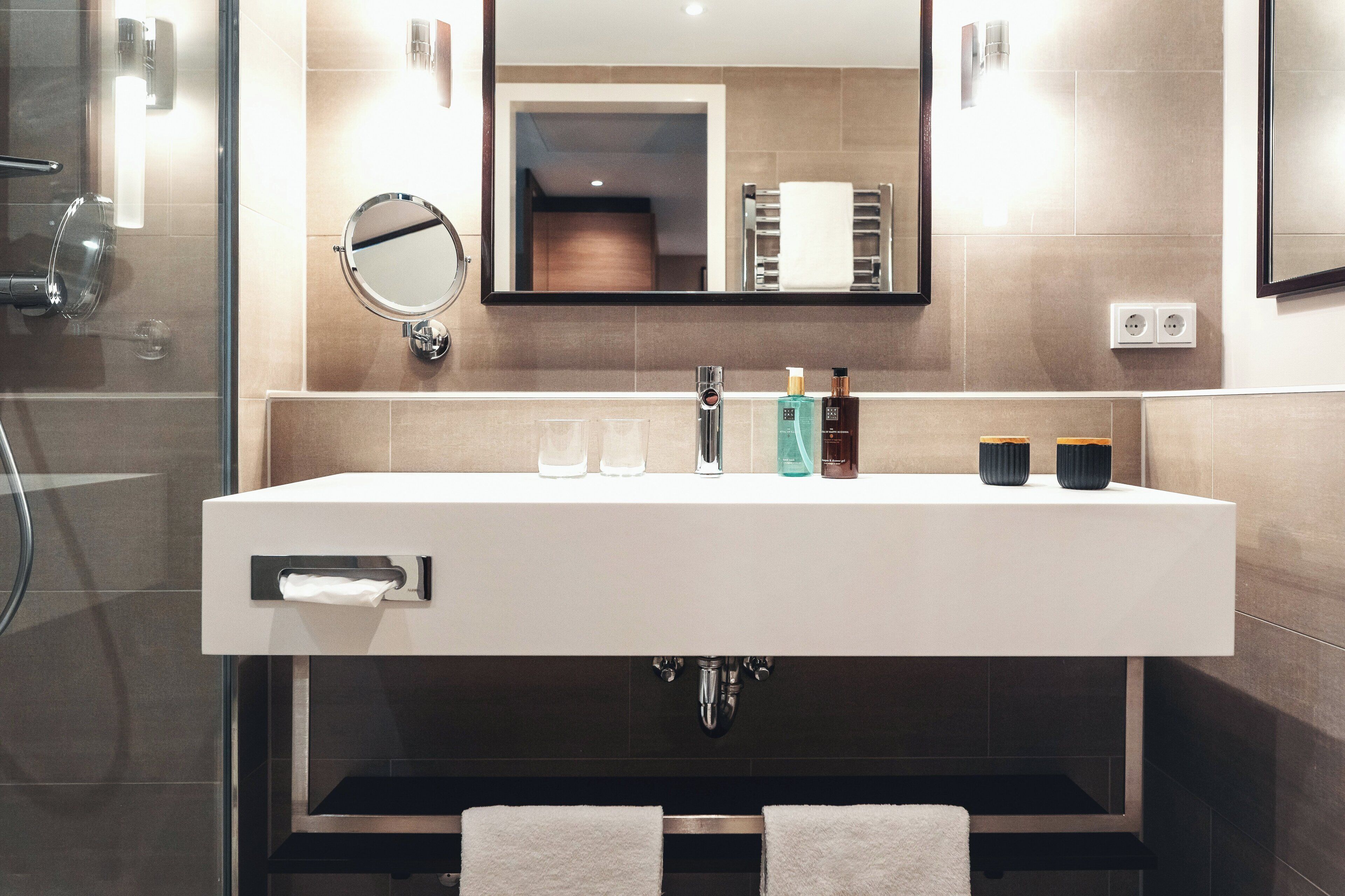 A modern bathroom with a large sink, mirror, and towel rack.