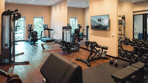 Une salle de sport équipée de matériel d’exercice, d’un miroir et d’un écran de télévision.