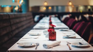 Un restaurant avec une longue table dressée pour le repas, agrémentée d’un centre de table décoratif.