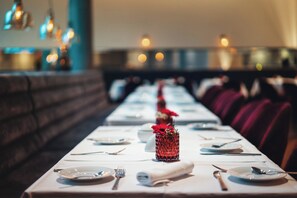 Ein Restaurant mit einem langen Tisch, gedeckt für ein Essen, mit einem dekorativen Mittelstück.