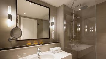 A modern bathroom with a large mirror, a sink, and a glass-enclosed shower.