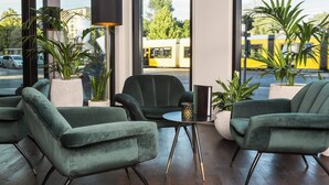 Un intérieur moderne avec des chaises recouvertes d’un tissu vert, une petite table et un lampadaire.