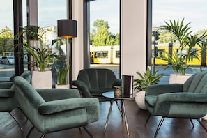 Ein modernes Interieur mit grünen Polstersesseln, einem kleinen Tisch und einer Stehlampe.