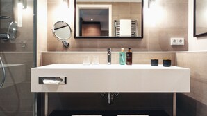 Ein modernes Badezimmer mit einem großen Waschbecken, einem Spiegel und zwei Handtüchern, die an Haken hängen.