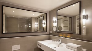 Ein modernes Badezimmer mit einem großen Spiegel, einem Waschbecken und einer Dusche.