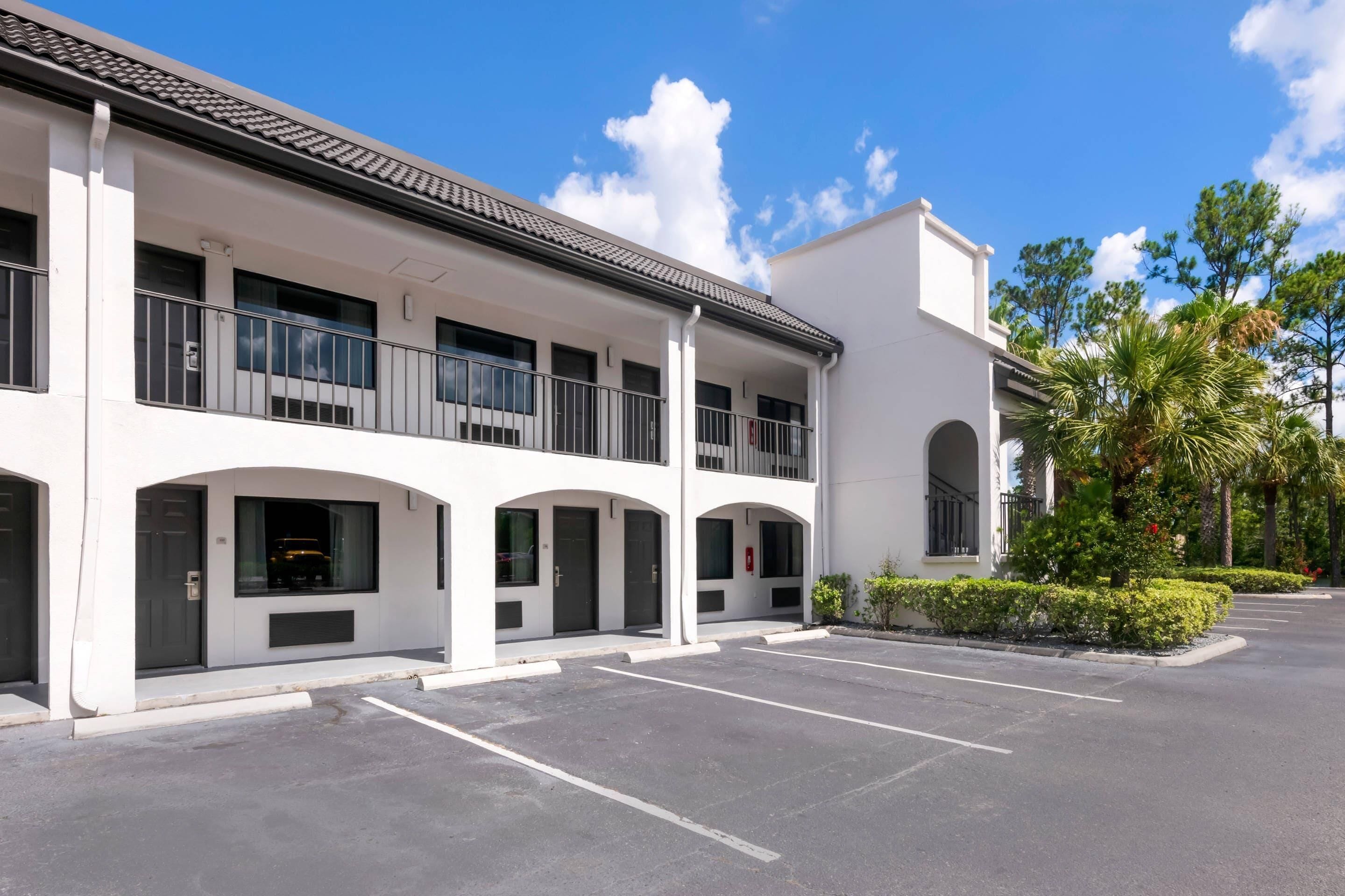 Un hôtel à plusieurs étages, doté d’une façade blanche, de balcons et d’un parking.
