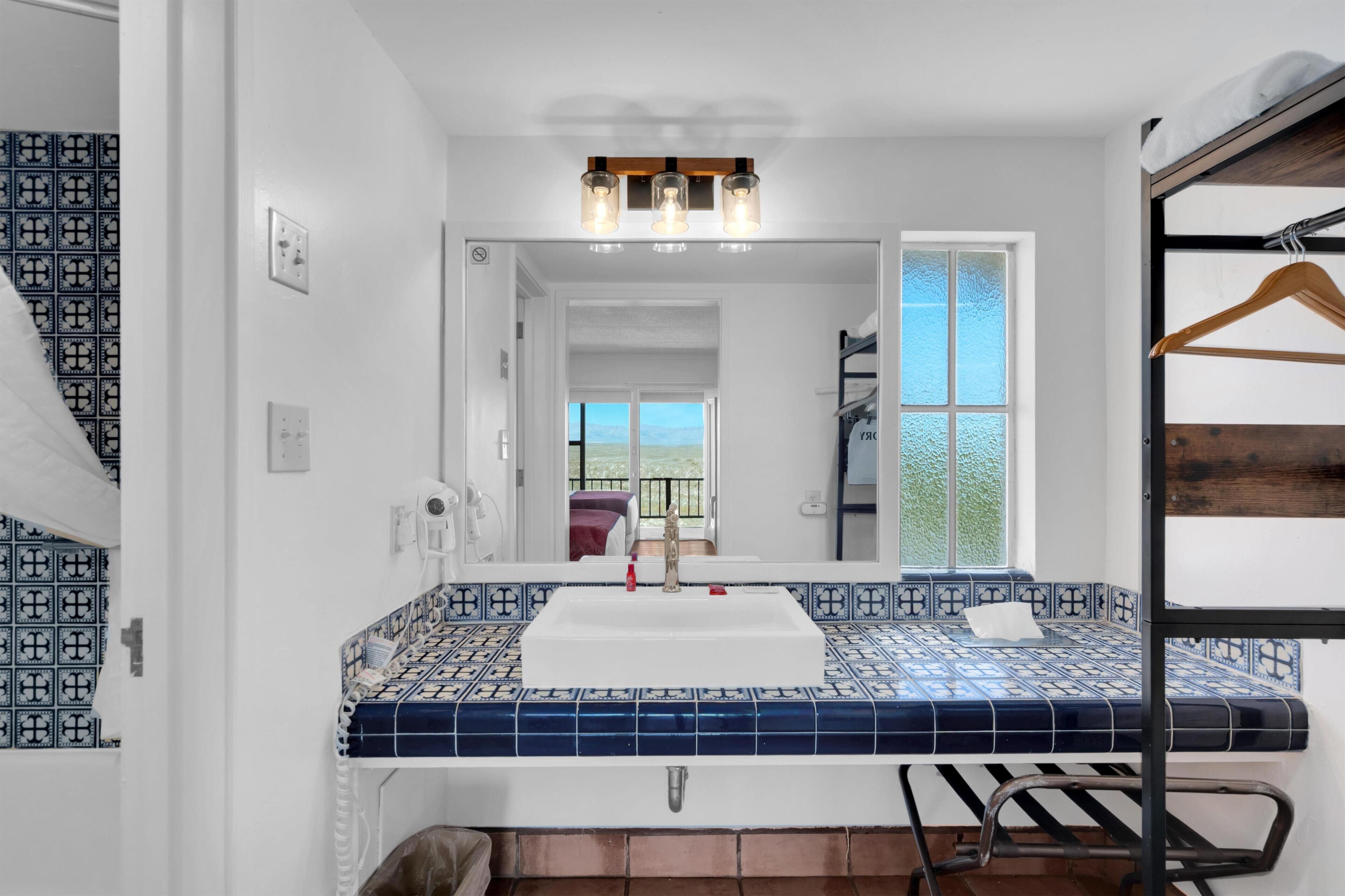 Un baño con un lavabo de azulejos, un espejo y un toallero colgante.