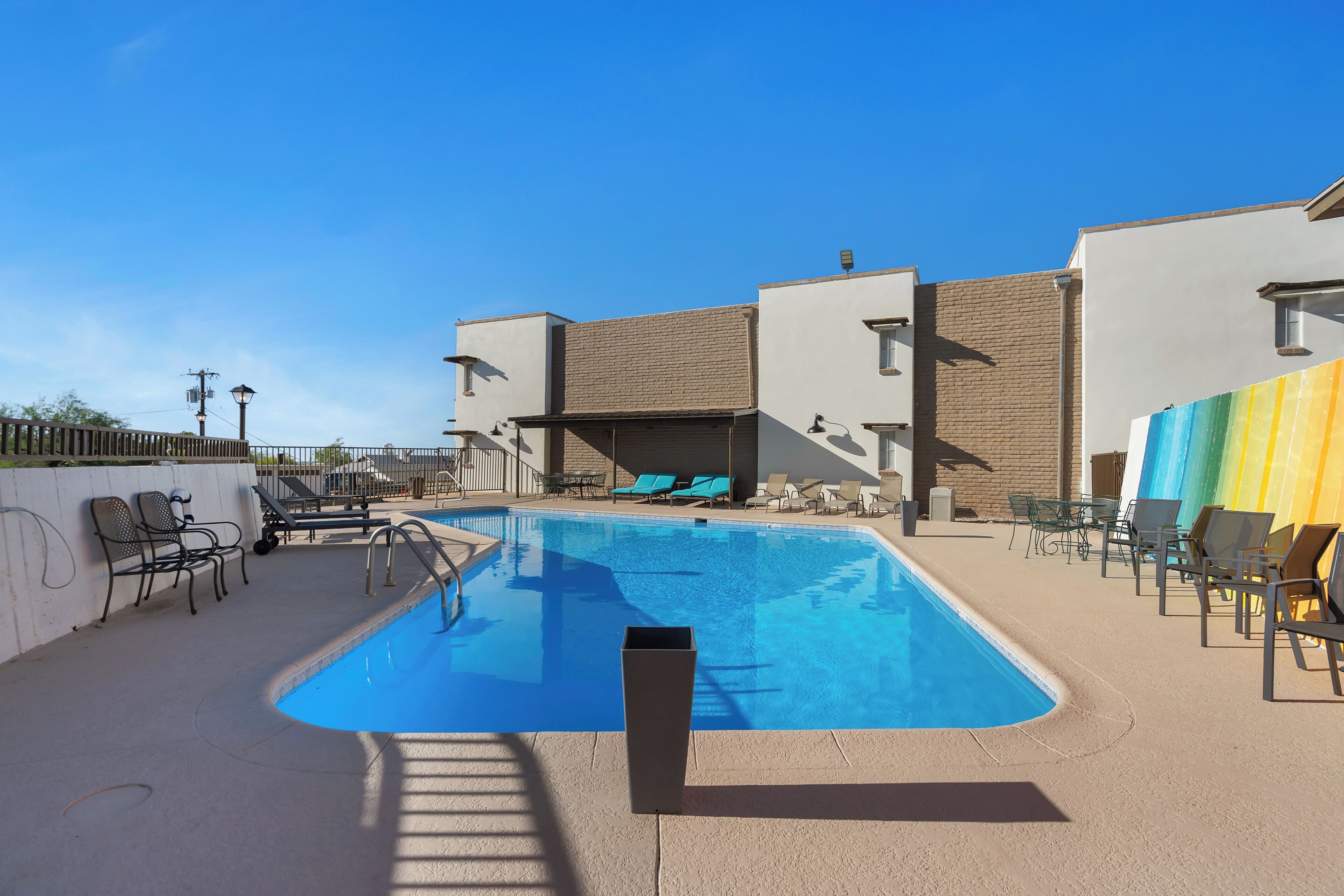 Una piscina con sillas de descanso y una zona de estar techada.