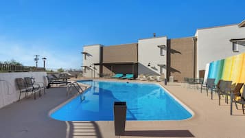 Una piscina con sillas de descanso y una zona de estar techada.