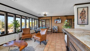 A spacious room with large windows, a pool table, leather chairs, and a wooden coffee table. - Tombstone Lookout Lodge, SureStay Collection by Best Western (Tombstone)