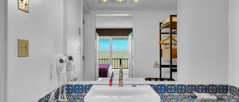 Un baño con un lavamanos grande, un espejo y vistas al balcón.