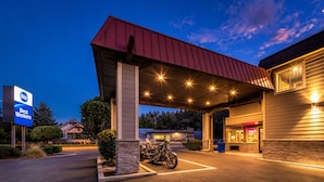 A Best Western hotel with a covered parking area, a motorcycle, and a clear sky. - Best Western John Day Inn (John Day)