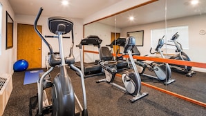 A gym with exercise equipment, a blue exercise ball, and a mirror reflecting the room. - Best Western John Day Inn (John Day)