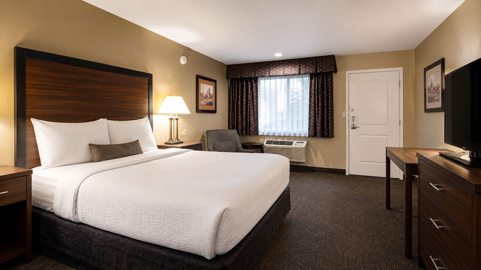 Hotelkamer met een groot bed, een bureau, een stoel, een televisie en een raam met gordijnen.