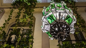 A chandelier with a geometric design, hanging in a room with a high ceiling and large windows. - Hotel Reina Cristina (Granada)