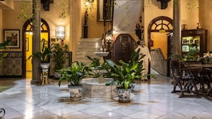 A spacious lobby with a marble floor, potted plants, and a staircase leading to upper floors. - Hotel Reina Cristina (Granada)