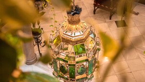 A chandelier with a green and gold design, a fireplace, and a tiled floor. - Hotel Reina Cristina (Granada)