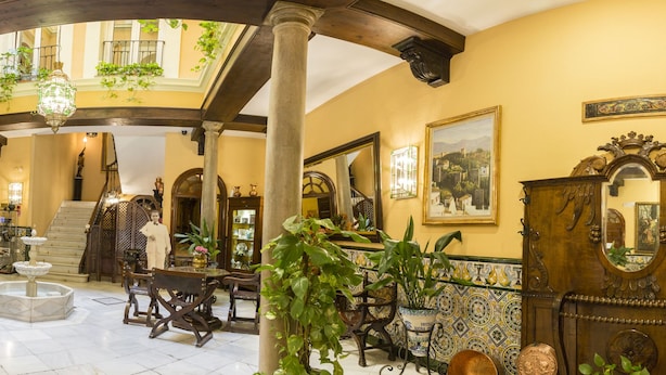 A grand lobby with high ceilings, ornate columns, and a central staircase. - Hotel Reina Cristina (Granada)