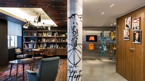 A modern interior with a central column featuring a heart design and the text "Heart Makes you Happy." There are bookshelves, a seating area with chairs and a table, and a bicycle mounted on the wall. - Le General Hotel (Paris)