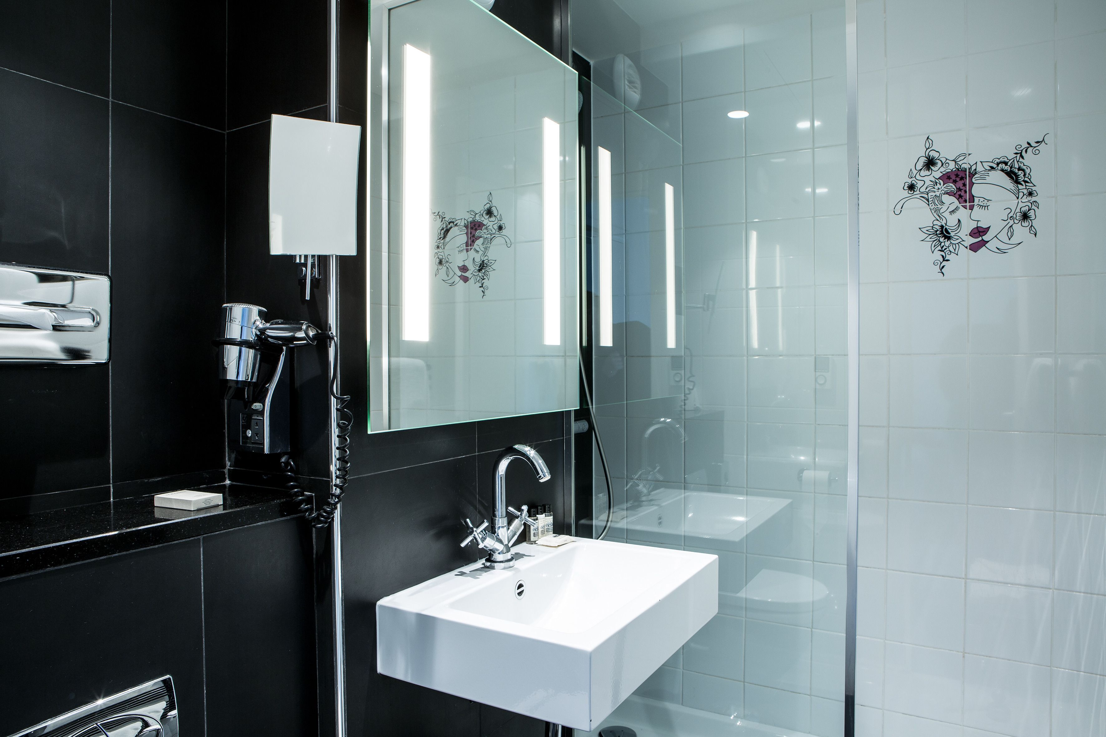 A modern bathroom with a white sink, chrome faucet, and a large mirror.