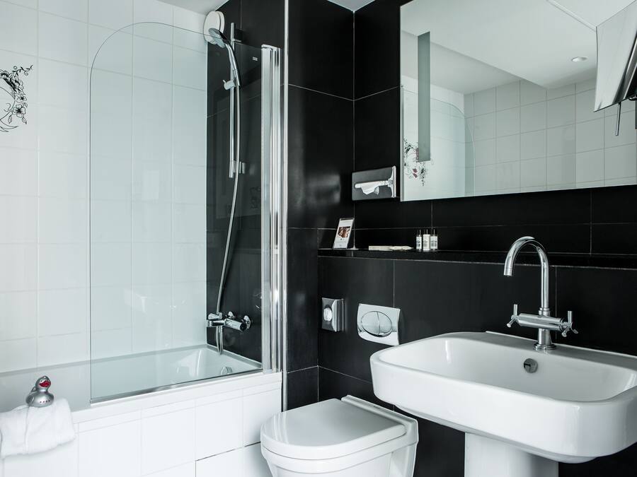 Un bagno moderno con doccia a vetro, lavandino bianco e WC.