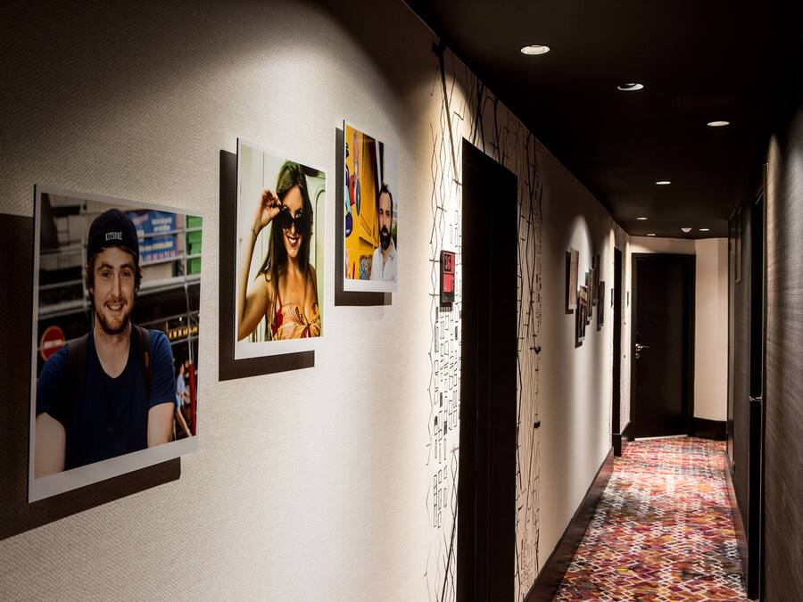 Ein Flur mit gerahmten Fotos an der Wand, einem gemusterten Teppich und einer Tür am Ende.