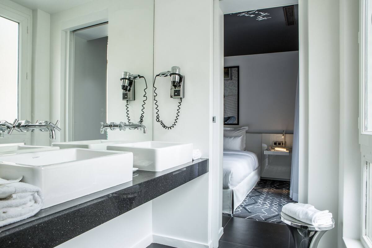 A modern bathroom with two sinks, a large mirror, and a shower area.