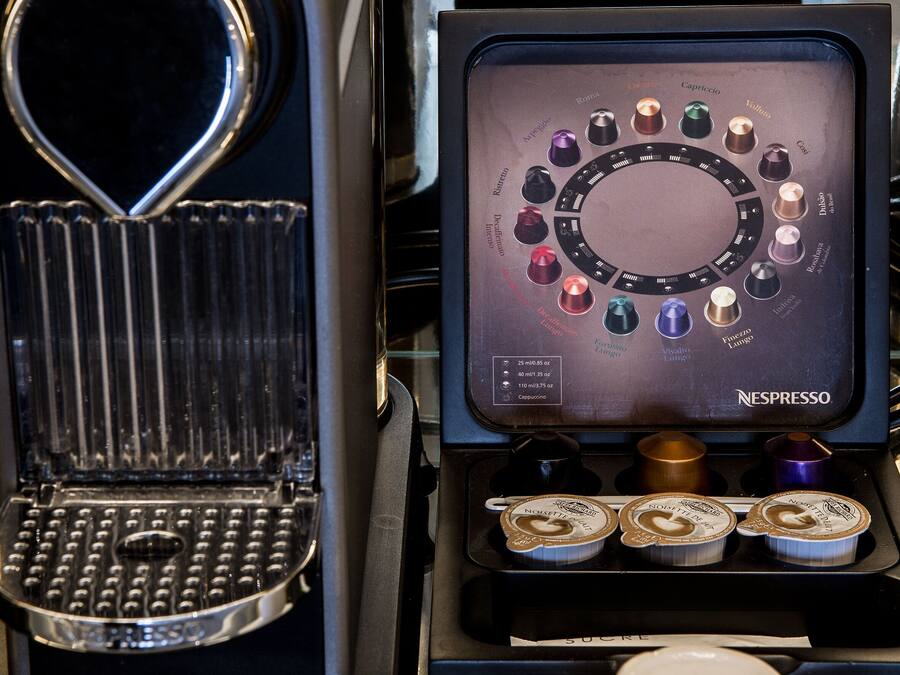 A Krups espresso machine with a display panel and a cup of coffee on a saucer.
