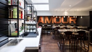 A modern restaurant interior with a large 'AMOUR' sign, wooden bar stools, and a variety of kitchen utensils on shelves. - Le General Hotel (Paris)