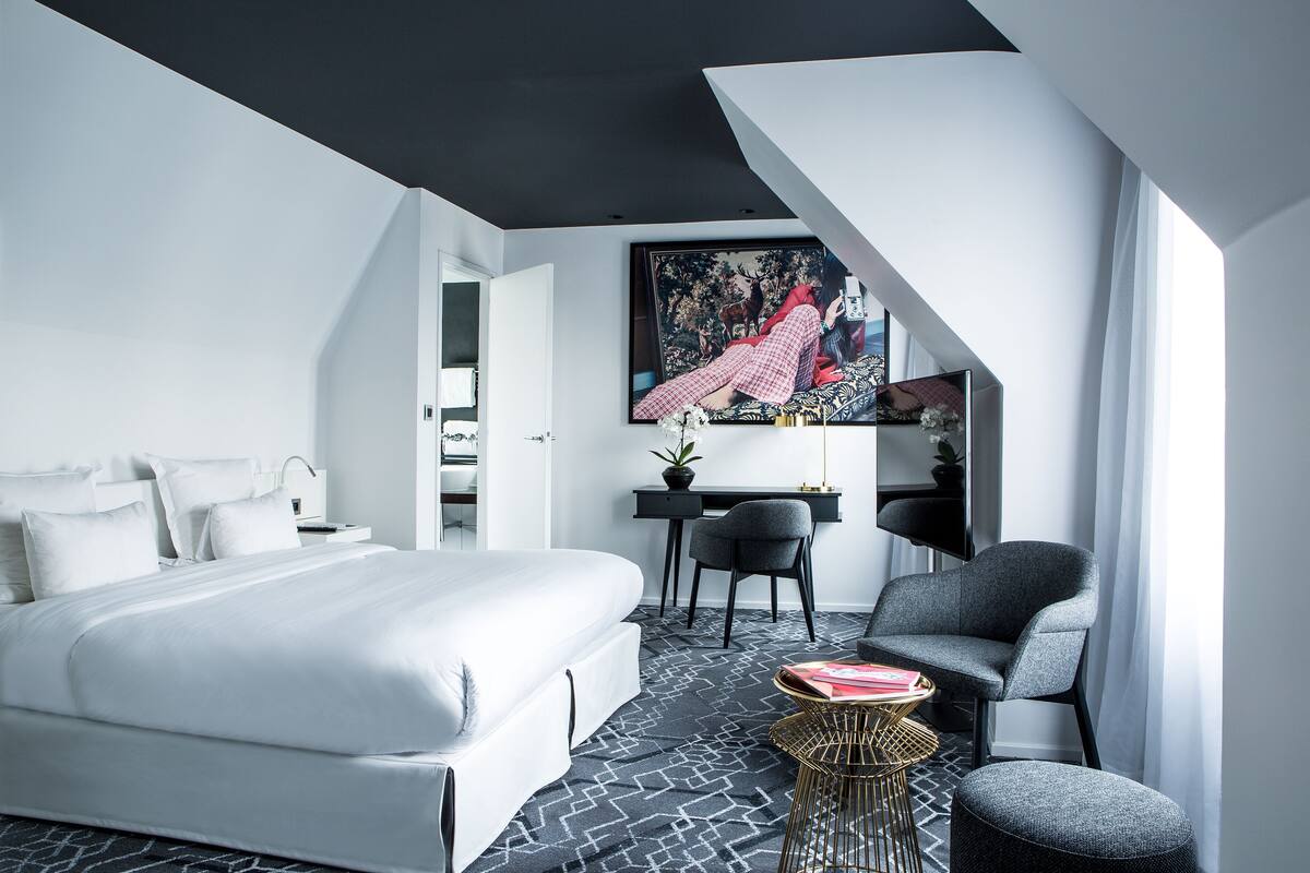 A modern bedroom with a large bed, a desk, and a chair.