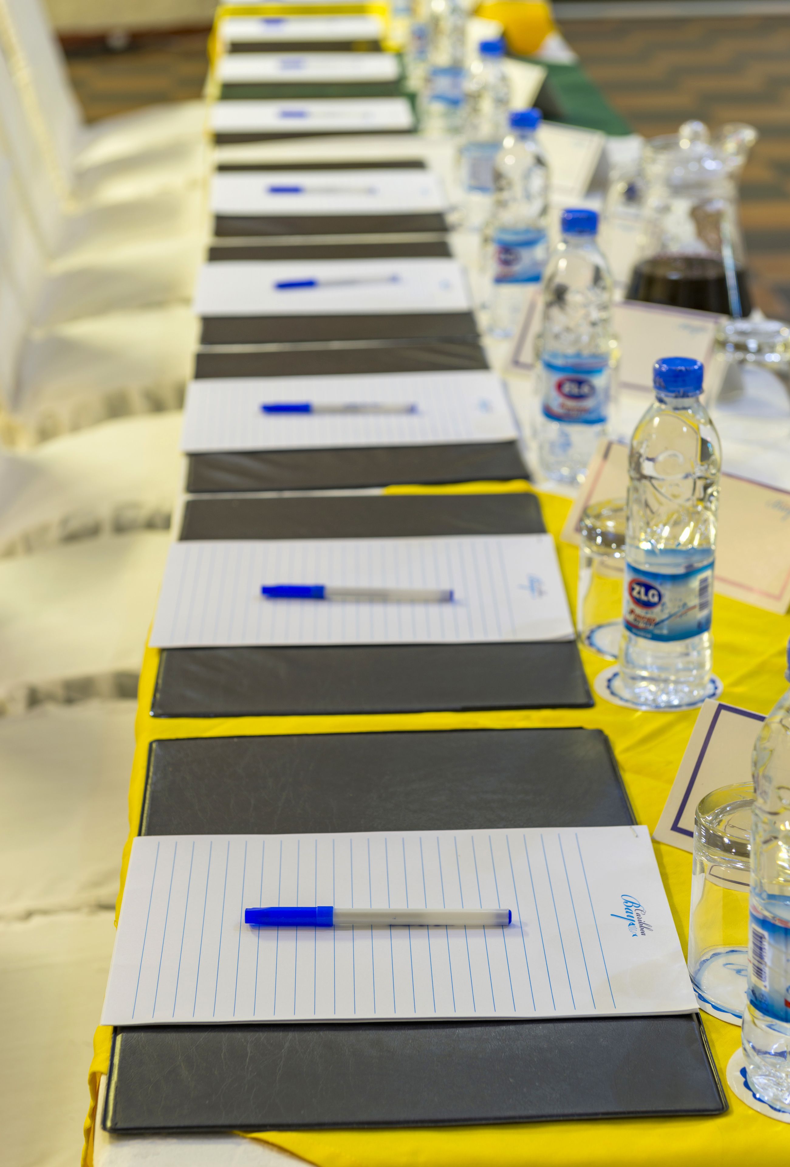 A conference table with lined notepads, pens, and water bottles.