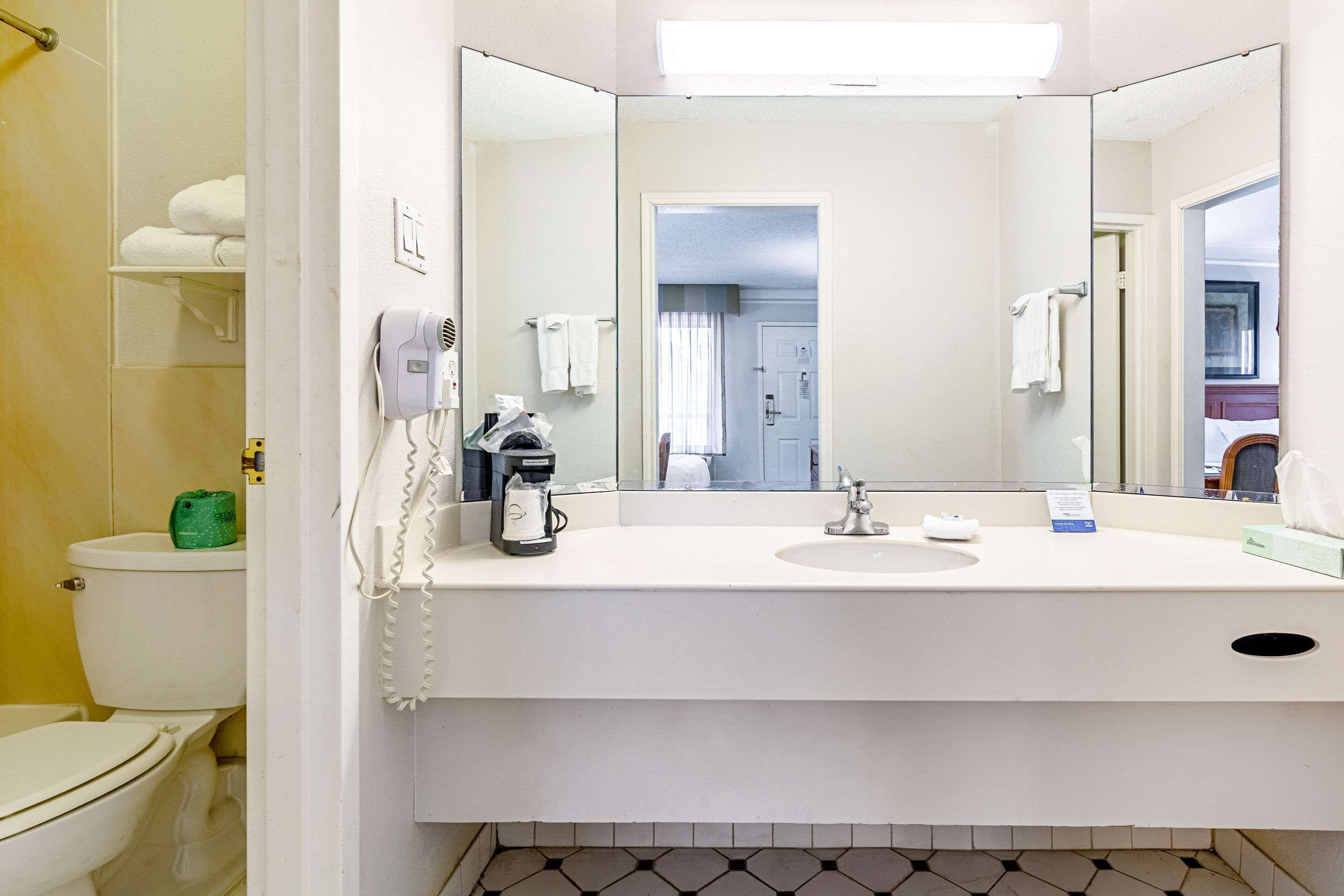 Un baño con lavamanos blanco, espejo, inodoro y zona de ducha.
