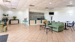 Un hall d’entrée spacieux avec un canapé vert, une table basse et un coin repas comprenant des chaises et des tables.