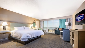 A hotel room with a large bed, a desk, a TV, and a balcony with a view. - Hampton Inn Virginia Beach-Oceanfront North (Virginia Beach)