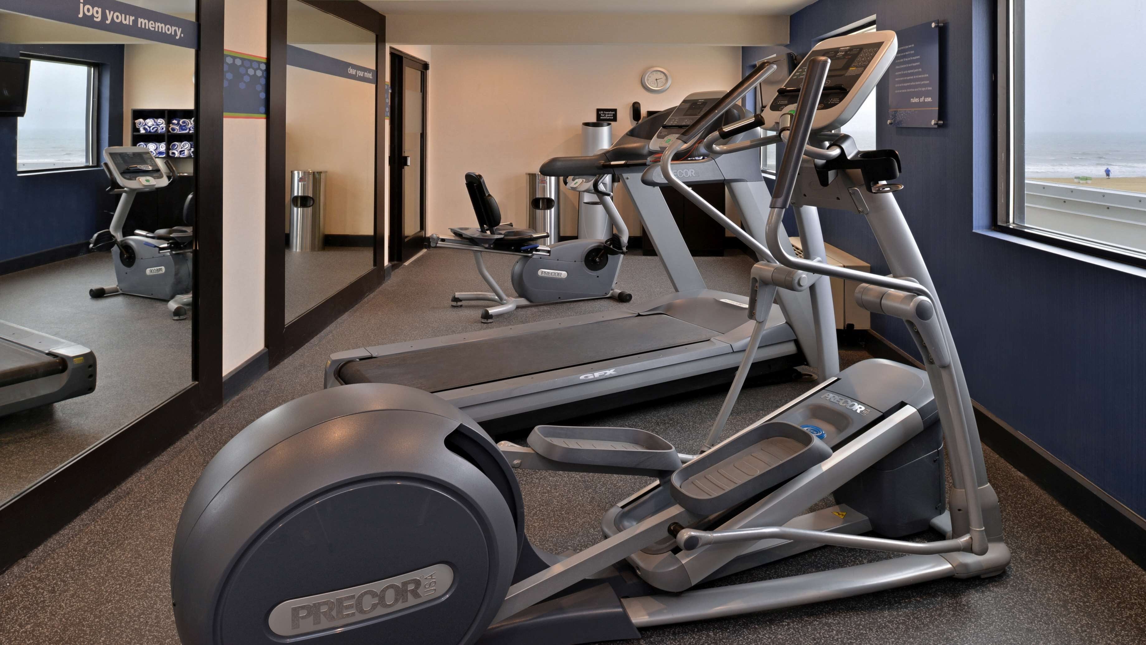 Un gimnasio con cintas de correr, elípticas y equipamiento de ejercicio.