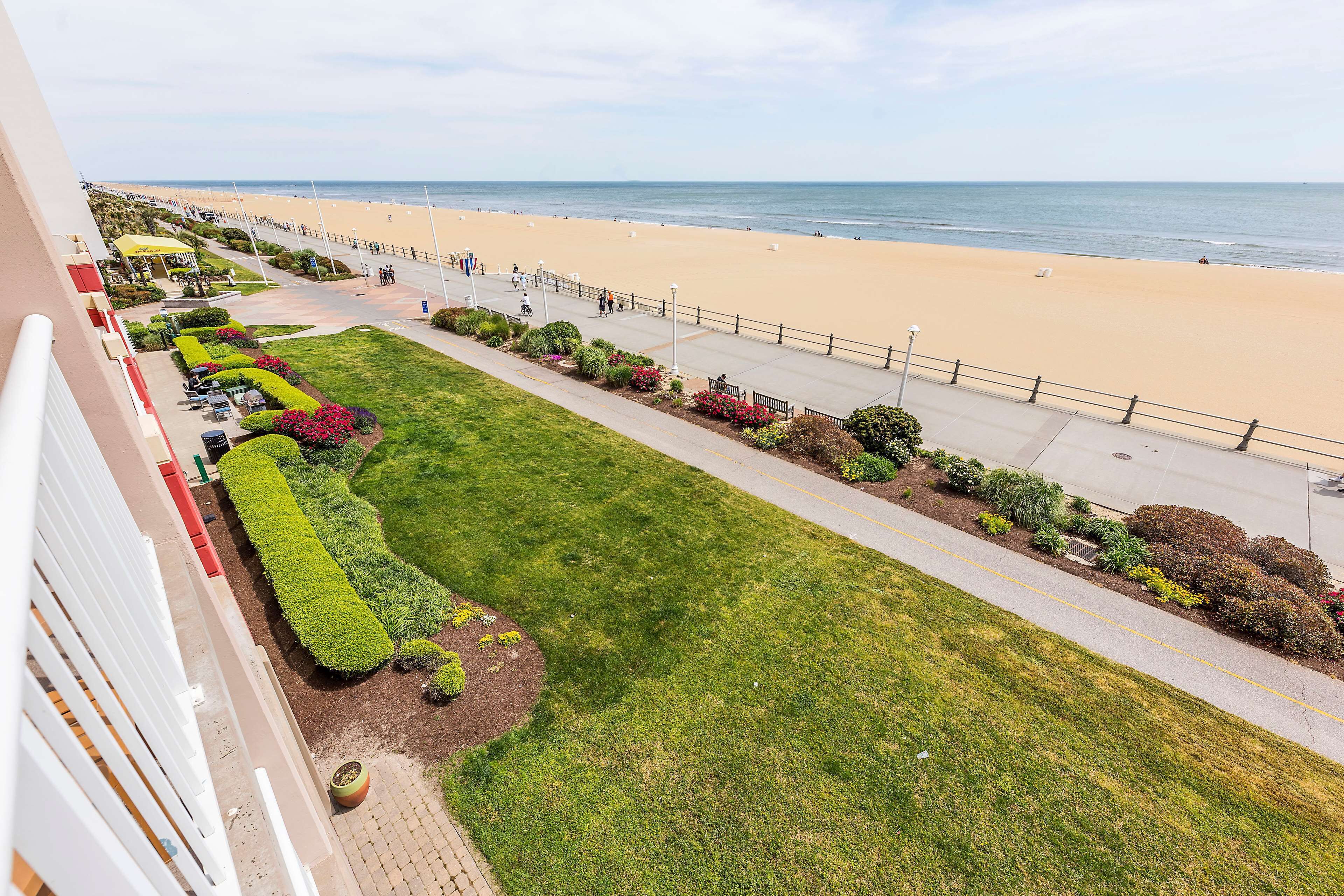 Un hotel sul lungomare con vista sulla spiaggia, un viale lastricato e prati curati.