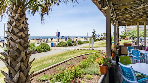 A covered outdoor seating area with a view of the beach and city skyline. - Hampton Inn Virginia Beach-Oceanfront North (Virginia Beach)