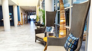 A lobby with wicker chairs, a yellow table, and a large window. - Hampton Inn Virginia Beach-Oceanfront North (Virginia Beach)