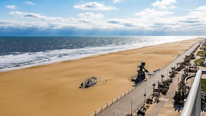 A beach with a paved walkway, a statue, and a clear view of the ocean. - Hampton Inn Virginia Beach-Oceanfront North (Virginia Beach)