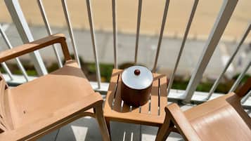 Un balcón con dos sillas de madera y una mesita con una maceta.