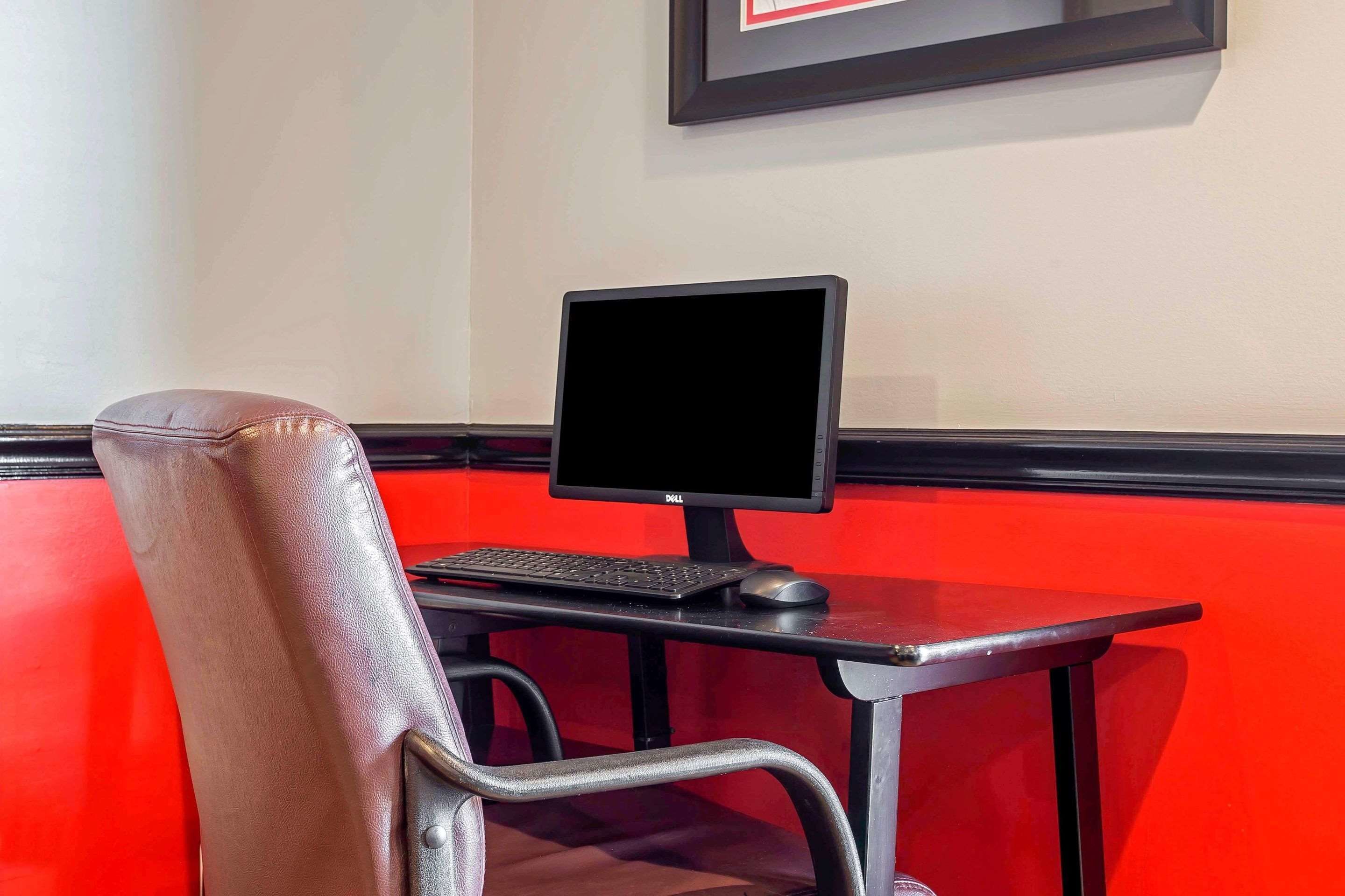 A computer desk with a monitor, keyboard, and mouse.